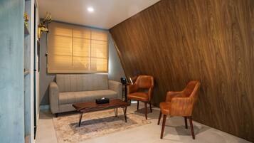 A modern living room with a sofa, two leather chairs, a coffee table, and a wooden accent wall.