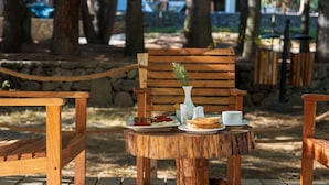 A wooden table with plates of food and a white vase.