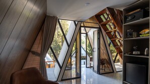 A modern interior with a large glass door leading to an outdoor area, a wooden bookshelf, and a leather chair.