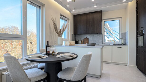 Una cocina moderna con una isla central, ventanas amplias y vista a un puente.