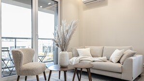 Una sala de estar moderna con un sofá, un sillón y una mesita con un jarrón de plantas secas.