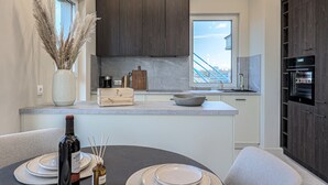 Una cocina moderna con armarios de madera oscura, un ventanal grande y un horno empotrado.