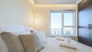 Un dormitorio con cama, almohadas, una mesita de noche con toallas, una ventana y un armario.