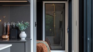 A narrow hallway with a bed, a small kitchen area, and a shower room.
