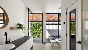 A modern bathroom with a large sink, a mirror, and a view of a hot tub through glass doors. - Bayside Grandeur with Heated Pool, Spa and Sauna plus each Bedroom has Ensuite (Bentleigh)