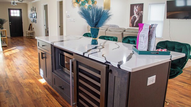 A kitchen with a marble countertop, a built-in stove, and a green chair.