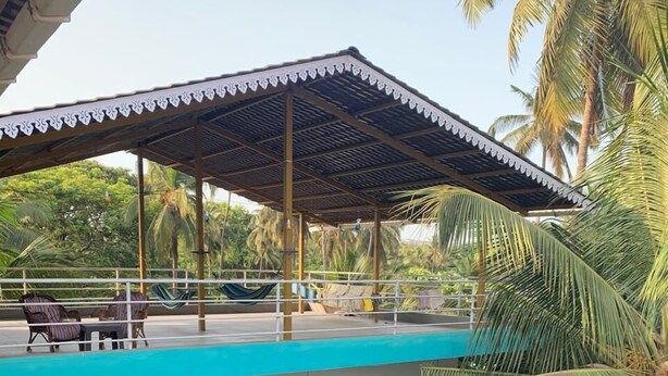Un bâtiment à deux étages doté d’une piscine située au niveau supérieur, entouré de palmiers.