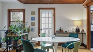 A cozy dining area with a round table, green chairs, and a wooden ceiling. - Great Fall pricing! Magical Views & Peaceful Vibes; private dock, kayaks, firepit, office! (Newtown)