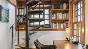 A home office with a spiral staircase, wooden bookshelves, a desk, and a chair. - Great Fall pricing! Magical Views & Peaceful Vibes; private dock, kayaks, firepit, office! (Newtown)