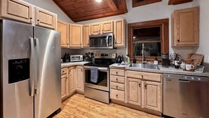 A modern kitchen with stainless steel appliances, wooden cabinets, and a wooden ceiling. - Great Fall pricing! Magical Views & Peaceful Vibes; private dock, kayaks, firepit, office! (Newtown)