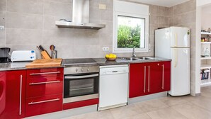 A modern kitchen with red and white cabinetry, a stainless steel range, and a built-in oven. - Mon Coeur by Interhome (El Port de la Selva)