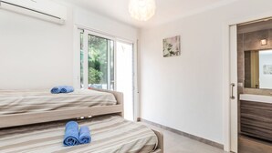 A modern hotel room with a large window, a bed with rolled towels, a bathroom with a mirror, and a hanging light fixture. - Mon Coeur by Interhome (El Port de la Selva)