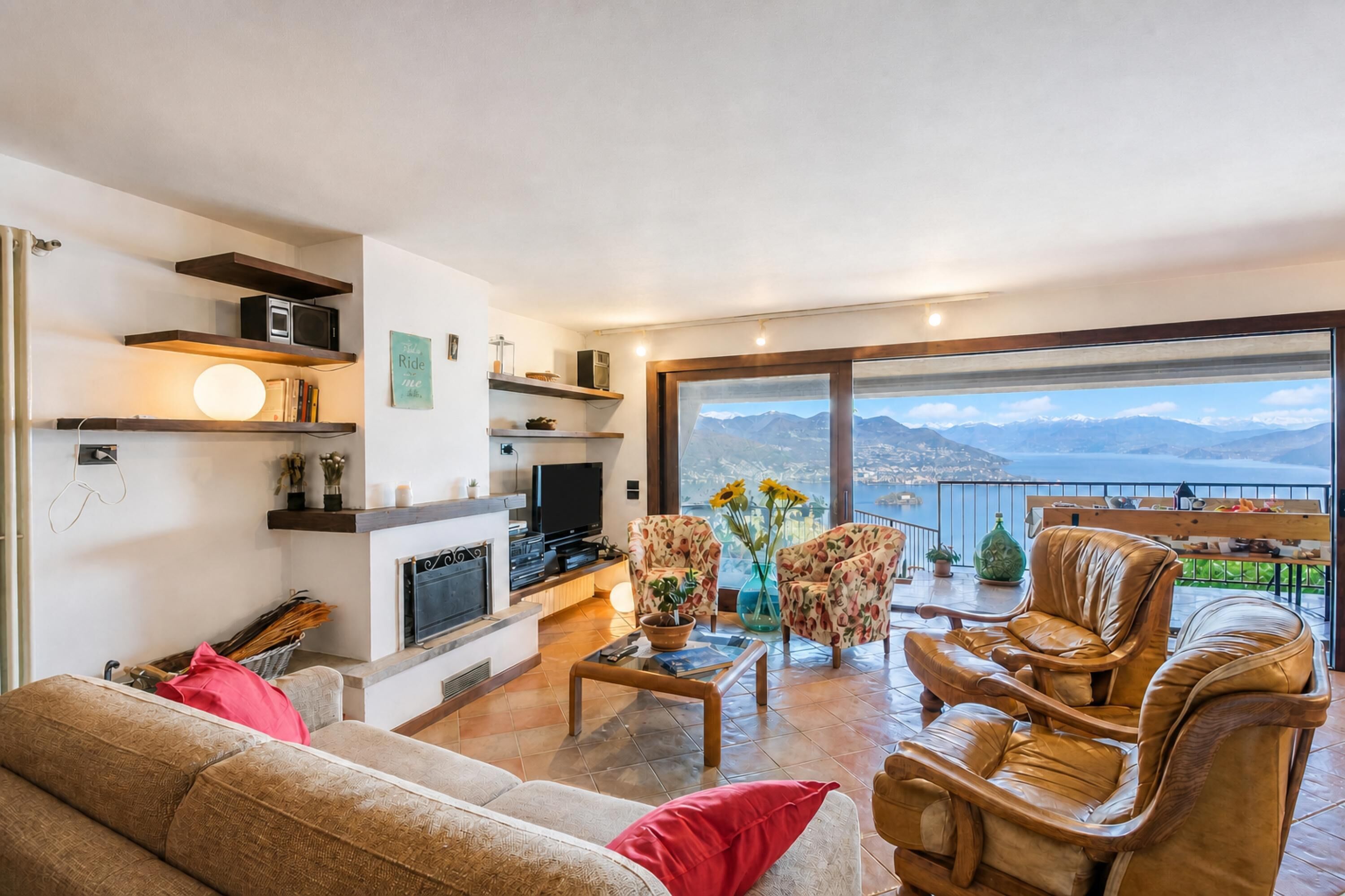 A modern living room with a fireplace, a television, and a view of the sea.