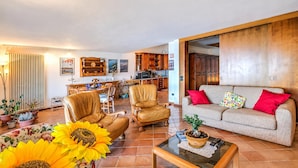 A spacious living room with a sofa, two leather chairs, a coffee table, and a dining area with a table and chairs. - Isola Bella: Lake Maggiore View Terrace in Stresa (Stresa)