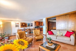 A spacious living room with a sofa, two leather chairs, a coffee table, and a dining area with a table and chairs. - Isola Bella: Lake Maggiore View Terrace in Stresa (Stresa)