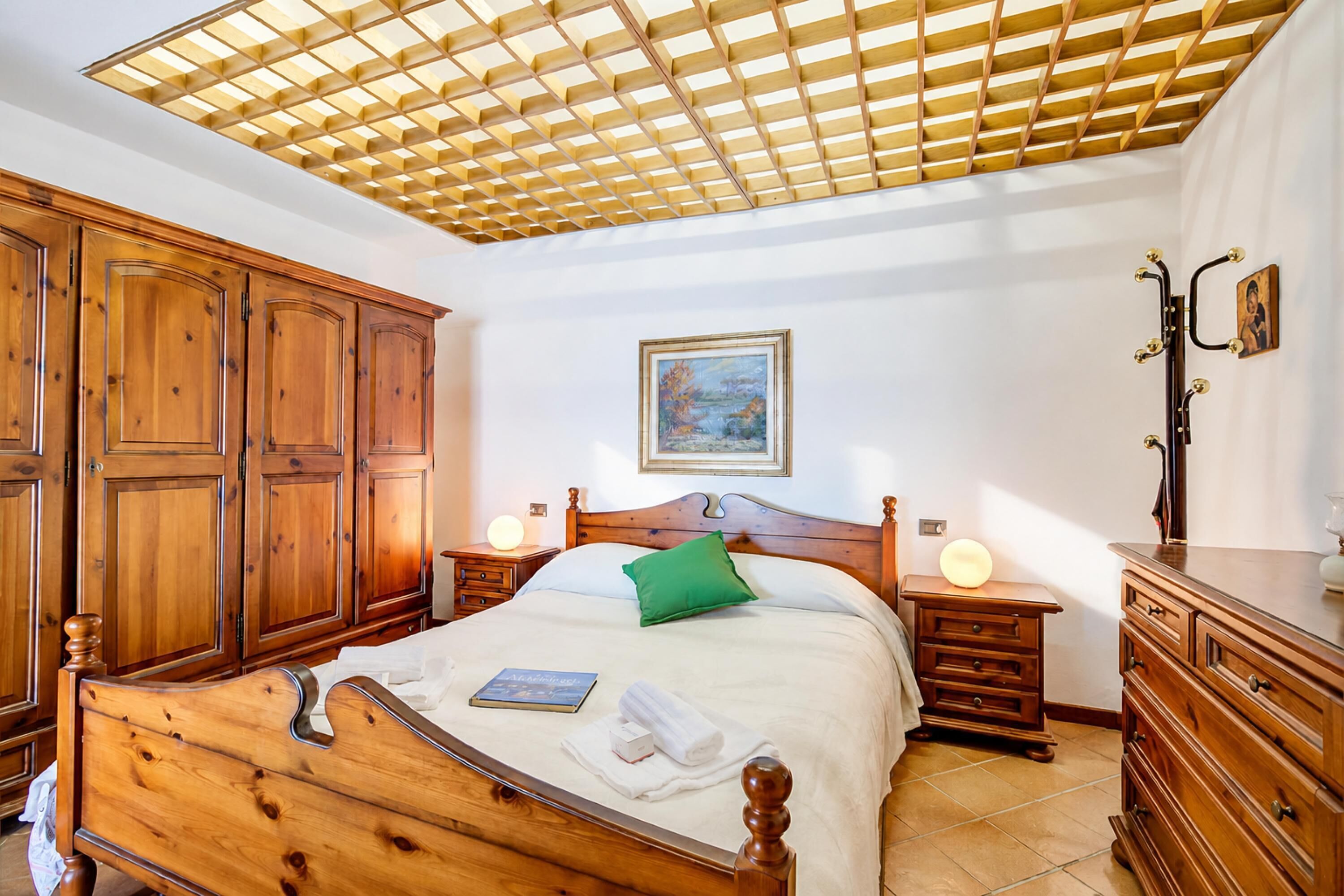 A bedroom with a wooden bed, nightstands, a dresser, and a ceiling fan.