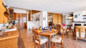 A spacious kitchen with wooden cabinets, a dining area with a round table and chairs, and a staircase leading to an upper level. - Isola Bella: Lake Maggiore View Terrace in Stresa (Stresa)