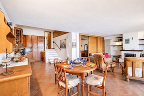 A spacious kitchen with wooden cabinets, a dining area with a round table and chairs, and a staircase leading to an upper level. - Isola Bella: Lake Maggiore View Terrace in Stresa (Stresa)