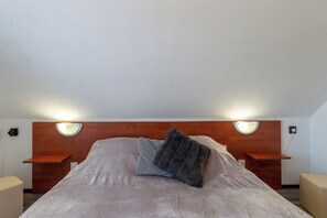 A neatly made bed with a headboard, two bedside tables, and wall-mounted reading lights. - Karesz Holiday Home (Zalakaros)