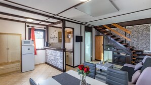 A modern kitchen with a built-in microwave, a dining area with a table and chairs, and a living room with a sofa and a fireplace. - Karesz Holiday Home /w Terrace & Garden (Zalakaros)