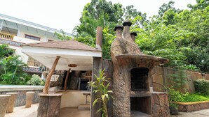 Un espacio de estar al aire libre de estilo rústico con estructuras de piedra y plantas en macetas.