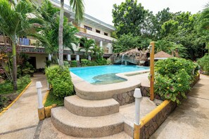 Relax by the serene pool surrounded by lush greenery and palm trees.