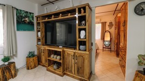 Una sala de estar con un mueble de madera para centro de entretenimiento, un televisor de pantalla plana grande y un espejo.