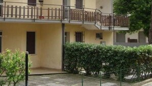 A multi-story residential building with balconies, a gated entrance, and a surrounding hedge. - Cosy apartment for 5 people with A/C, terrace and pets allowed (Rosolina)