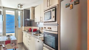 Een moderne keuken met roestvrijstalen apparatuur, een eethoek met een tafel en een uitzicht door het raam.
