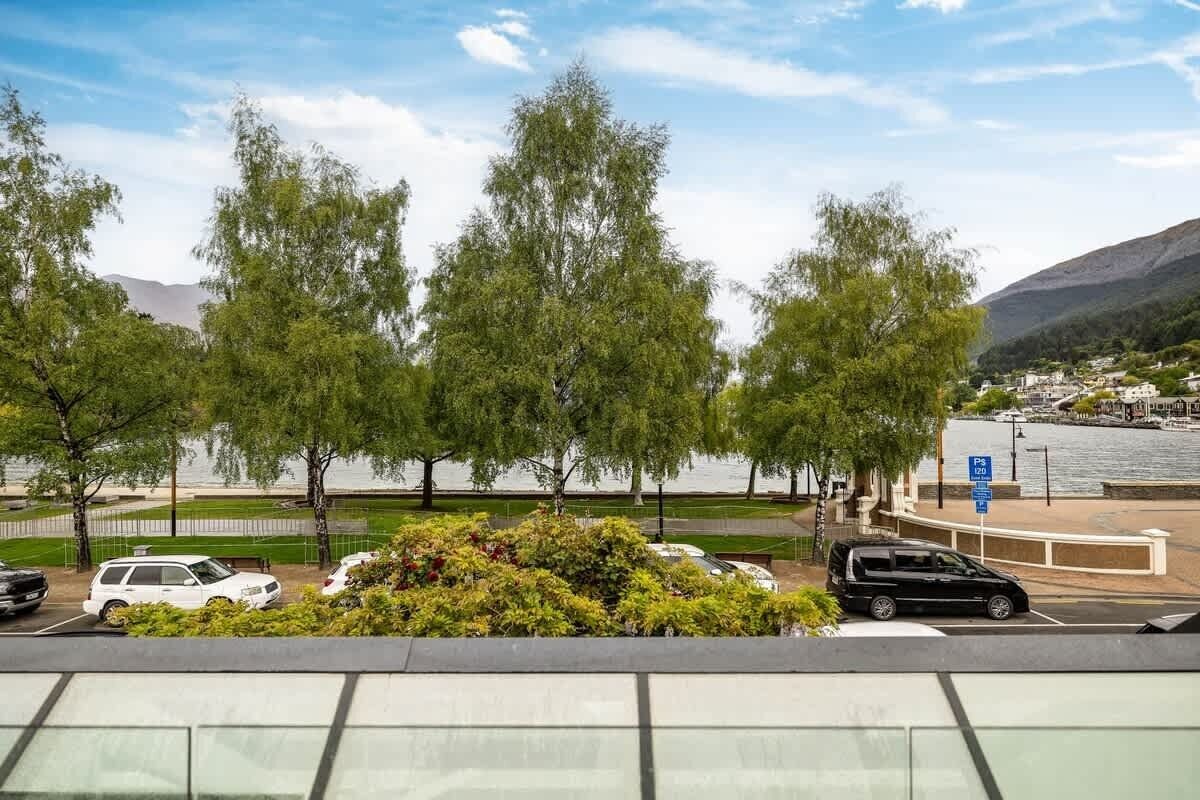 A parking area with trees and a view of a body of water and mountains.