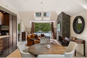 Un salon moderne avec une cheminée en pierre, une table ronde en bois et un ensemble de canapés.