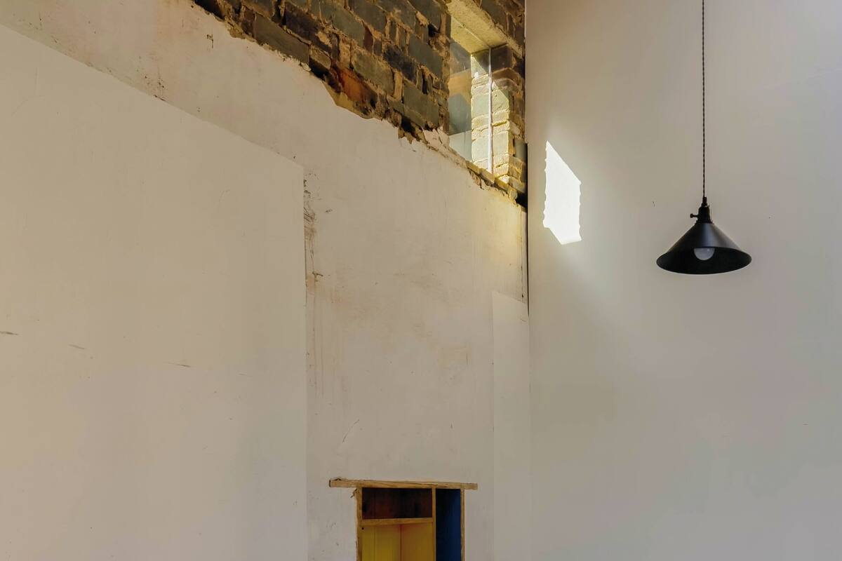 Une chambre avec deux lits simples, une petite fenêtre et un luminaire suspendu.