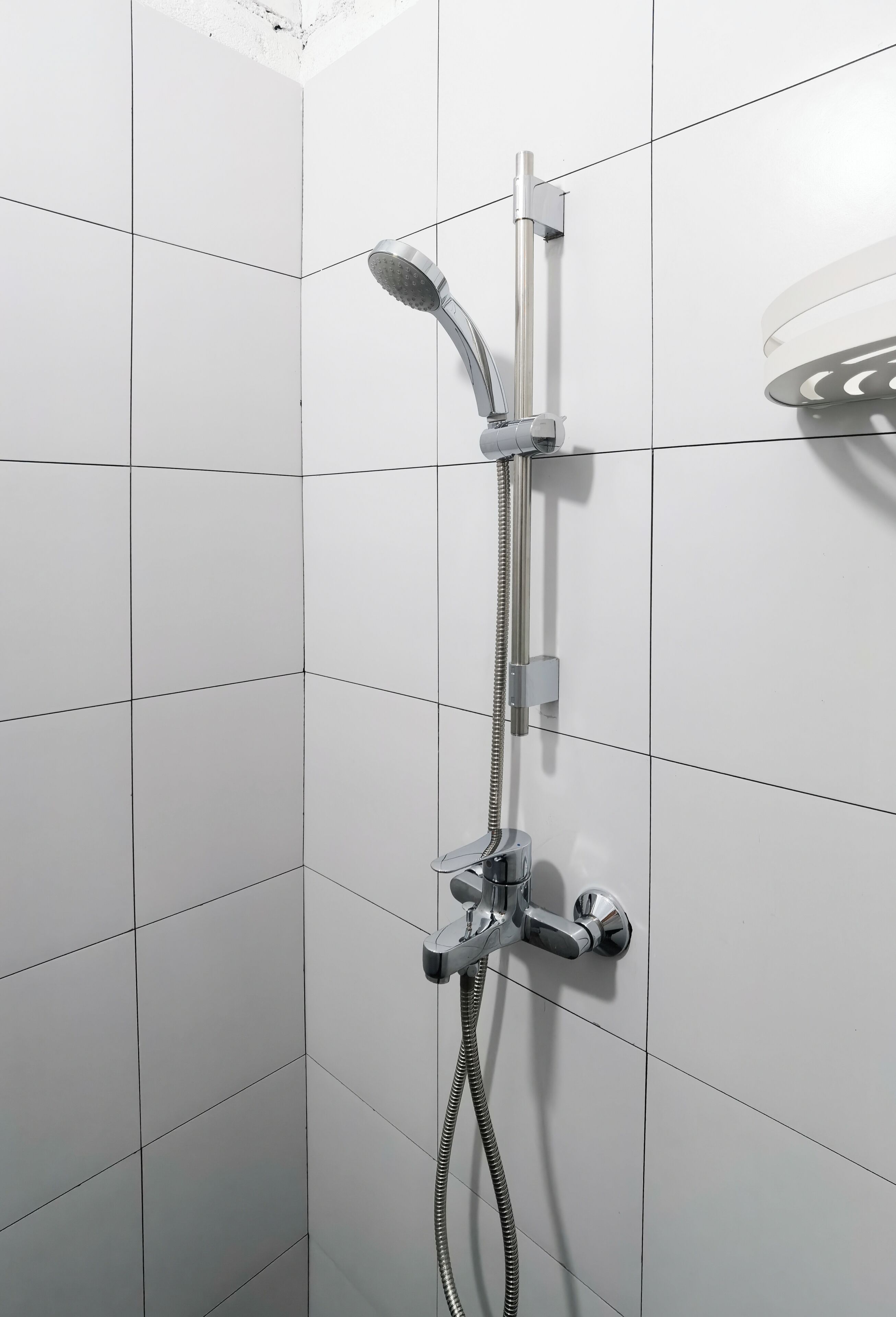 A shower with a handheld showerhead and a wall-mounted faucet.