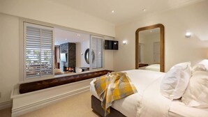 Une chambre à coucher avec un lit, un grand miroir, une télévision et une cheminée.