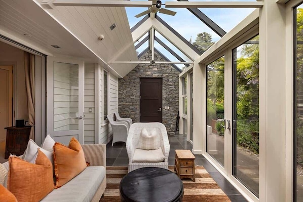 A covered porch with a stone wall, a ceiling fan, and a view of the outdoors.