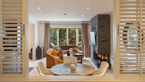 Un salon moderne avec une cheminée en pierre, des sièges confortables et une grande fenêtre agrémentée de rideaux.