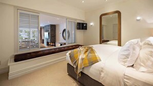 Une chambre à coucher avec un grand lit, un miroir, une télévision et une cheminée.