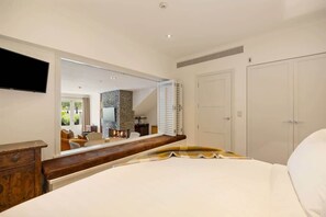 A bedroom with a bed, a TV mounted on the wall, a wardrobe, and a bathroom visible through an open door.