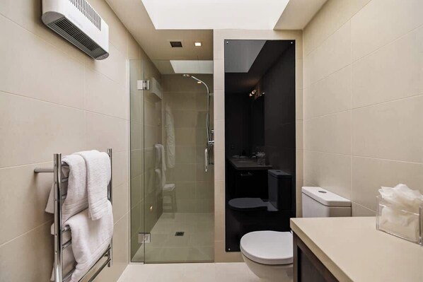 A compact bathroom with a glass-enclosed shower, a toilet, and a sink.