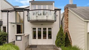 A two-story house with a balcony, a front door, and a small patio area.