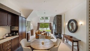A modern kitchen with dark wood cabinets, a round dining table, and a stone fireplace. - Creighton 1- Spacious Lakeshore Apartment (Queenstown)
