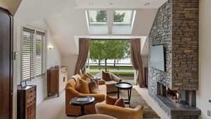 A modern living room with a stone fireplace, comfortable seating, and large windows. - Creighton 1- Spacious Lakeshore Apartment (Queenstown)