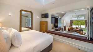 A bedroom with a bed, a large mirror, a TV, and a view of a balcony with outdoor furniture. - Creighton 1- Spacious Lakeshore Apartment (Queenstown)