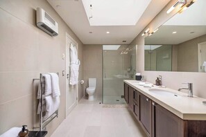 A modern bathroom with a glass shower enclosure, a walk-in vanity, and a large mirror.