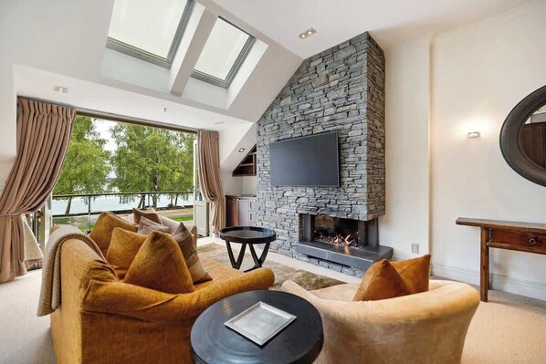 A modern living room with a stone fireplace, comfortable seating, and a large TV.