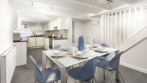 A modern kitchen with white cabinets, a black countertop, and a dining area with a white table set for four. - Salubrious Cottage -  a cottage that sleeps 6 guests  in 3 bedrooms (St Ives)