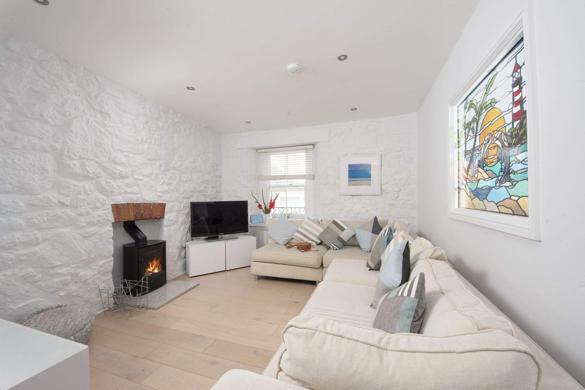 A living room with a fireplace, a television, a sofa, and a large window.