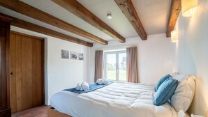 Une chambre à coucher avec un lit en bois, une fenêtre avec des rideaux et une vue sur l’extérieur.