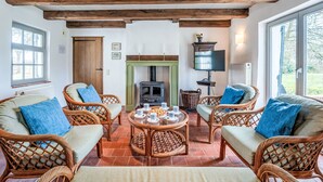 Un salon chaleureux avec des meubles en osier, une cheminée et un téléviseur.