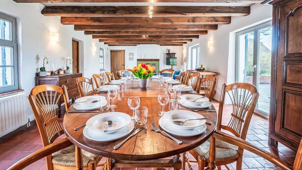 Une salle à manger avec une table en bois dressée pour le repas, entourée de chaises en bois.